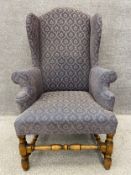 A Jacobean style wingback armchair on turned oak stretchers and supports, in a needlework