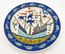 An Iznik style charger with galleon decoration in a presentation box. Dia.33cm.