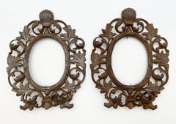 A pair of distressed gilt spelter picture frames with scallop shell crestings and scrolling