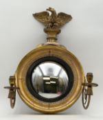 A Regency giltwood and ebonised convex girandole with a pair of scrolling gilt metal candle sconces,