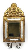 A gilt metal Dutch repousse cushion style mirror with an ornate rocaille cresting, the bevelled