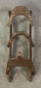 A wood framed iron and brass clad camel stool. L.135cm