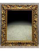A carved giltwood Florentine style mirror with an all over scrolling and pierced foliate design,