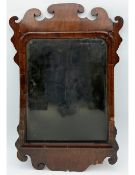 A Georgian walnut fret carved mirror having a shaped and scrolling cresting above a moulded frame