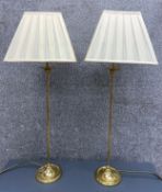 A pair of modern polished brass table lamps, with narrow stems on circular spread bases. With