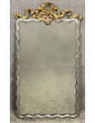 A 19th century French wall mirror with a carved giltwood scrolling ribbon cresting, which sits above