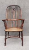 An early 19th century Windsor hooped back yewwood armchair with elm seat raised on crinoline