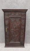 An early 18th century carved oak wall cabinet fitted with shelves. H.81.5 W.51 D.23cm