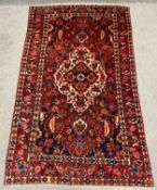 A handmade Persian Hamadan rug having an all over foliate design over a red field, with a central