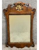 A Georgian walnut fret carved mirror having a shaped and scrolling cresting with a central