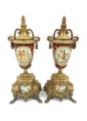 A pair of continental brass and Sevres style porcelain clock garnitures with scenes of courting