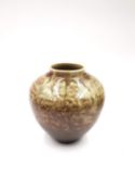 A studio pottery vase with a brown and mottled green glaze, on a narrow foot with makers mark to the