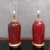A pair of Sang de Boeuf glazed Oriental style vase lamps with gilt lids. H.74cm.