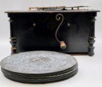 A late 19th century ebonised polyphon; Atlas Organette, together with 19 metal discs. H.23 W.45 D.