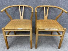 A pair of contemporary ash wishbone chairs in the style of Hans Wegner, with cushioned woven rush