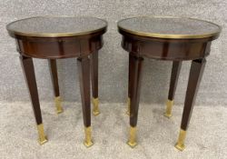 A pair of circular Empire style hardwood side tables with glass plate tops and a brass trim,