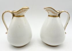 A pair of 19th century porcelain jugs with gilt foliate and laurel wreath design. Possibly Spode.