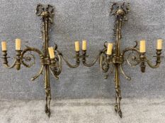 A pair of Rococo style brass wall sconces, each having a central scroll culminating in a bow