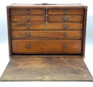 A late 19th century travel collectors cabinet with a fall-front door opening to reveal four short