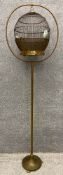 A vintage brass wire bird cage of globular form, hanging on a narrow pole stem leading down to a