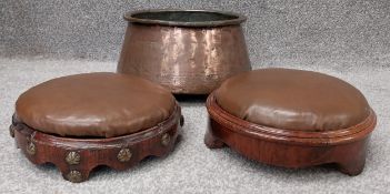 Two leather footstools, and a large copper pot. One of the footstools on a shaped walnut and brass