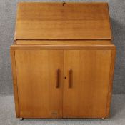 A mid-century oak writing bureau with a fall front and fitted interior, over two cabinet doors