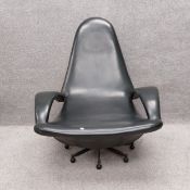 A mid-century low swivel lounge armchair in black vinyl on casters. H.102cm