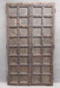 A pair of large early 19th century carved hardwood, panelled Moroccan doors with brass and iron