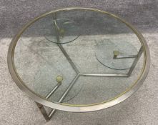 A mid-century circular glass, steel and gilt coffee table with three small, circular glass swivel-