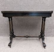 A 19th century aesthetic movement ebonised fold over card table on fluted, turned and stretchered