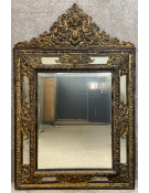 A large 19th century Dutch repousse brass and ebonised cushion mirror with an embossed scrolling