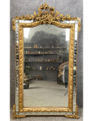 A 19th century French gilt-gesso and glass panelled cushion style mirror with and ornate floral