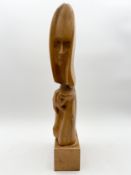 A mid-century carved teak abstract figural sculpture on a plinth base by Robert De Quin, signed to