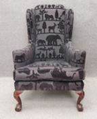 A large Georgian style wing back armchair, upholstered in animal print fabric, on short cabriole