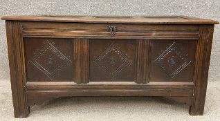 An 18th century oak coffer with a panelled lid above three carved panels to the frieze, over a