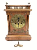 An Art Nouveau oak bracket clock with an embossed stylised brass dial surrounded with brass