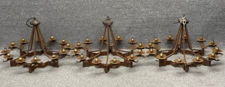 Three wrought iron continental chandeliers with twelve branches and scrolling finials. With