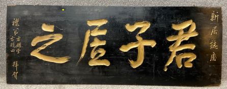 A 19th century Japanese lacquered sign with carved and gilt calligraphic characters. H.52 W.137cm.