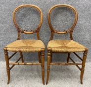 A pair of 19th century mahogany carved balloon back bedroom chairs with rush seats. H.84cm.