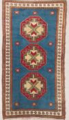 A Turkish Kars woollen rug with three central medallions over a teal field, bordered with a