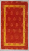 A contemporary woollen rug with an allover repeating stylised rosebud design over an iron red