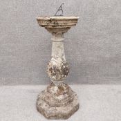 A carved stone sundial with a patinated bronze plate on a turned top above a baluster form stem on
