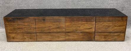 A contemporary teak TV cabinet with an inset polished fibreglass top above a wide central cabinet