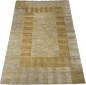 A mid to later 20th century wool rug with an abstract block pattern in mustard and oat over a