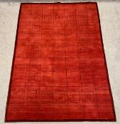 A hand knotted Nepalese rug with a geometric design in black over a red field with a dark red