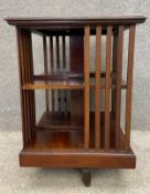 An Edwardian mahogany two tiered revolving bookcase having a moulded top over a half slatted and