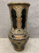 A large Moroccan ceramic urn clad in allover engraved brass, copper, and white metal, on a narrow
