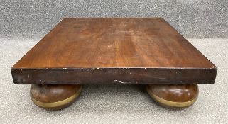 A mid-century Eastern style low mahogany coffee table on large bun supports with brass collars. With