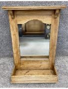 A pine wall mounted mirror with a moulded and bracketed cornice above a shaped frieze framing the