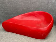 A mid-century red fibreglass settee sofa of tapering kidney shape form. H.70 W.157cm.